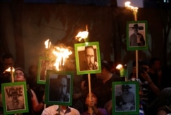 FILE - Journalists and demonstrators hold up pictures of slain journalist Javier Valdez Cardenas, at the Interior Ministry building in Mexico City, Mexico, May 16, 2017.