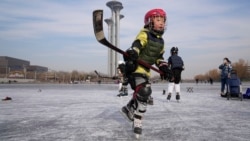 A child plays ice hockey near the Beijing Olympics Tower in Beijing, China January 18, 2022. (AP Photo/Ng Han Guan)