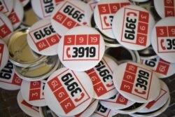 Badges showing an emergency phone number created to fight domestic violence are pictured, Sept. 3, 2019, at the hotel Matignon, the French prime minister's official residence in Paris, at the outset of a multiparty debate on domestic violence.