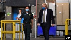 PM Inggris Boris Johnson, mengenakan masker berbincang dengan paramedis Cindy Fu saat meninjau Layanan Ambulans London "NHS Trust", 13 Juli 2020.