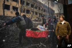 World Press Photo of the Year award winner, Associated Press photographer Evgeniy Maloletka, poses in front of his winning image prior to a press conference announcing the winners in Amsterdam, Netherlands, April 20, 2023.