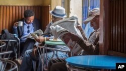 FILE - In this Oct. 10, 2016 file photo, Ethiopian men read newspapers and drink coffee at a cafe during a declared state of emergency in Addis Ababa, Ethiopia. Since 2015 there have been wide-ranging internet shutdowns.