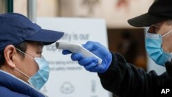 A security guard takes the temperature of a customer at a shopping precinct in Sydney, Australia, Jan. 3, 2021.