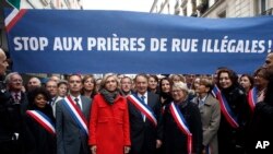 Clichy la Garenne's mayor Remi Muzueau, center right, and President of the Regional Council of the Ile-de-France region Valerie Pecresse, center left, demonstrate against Muslim street prayers, in the Paris suburb of Clichy la Garenne, Friday, Nov. 10, 2017. Clichy Muslims had been renting a prayer hall from City Hall, but the town's mayor decided to turn that space into a library. The dispute reflects nationwide problems with mosque shortages.