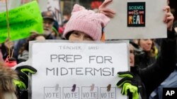 ស្ត្រី​ម្នាក់​កាន់​ស្លាកសញ្ញា​ផ្សព្វផ្សាយ​ពី​ការ​បោះឆ្នោត​ពាក់​កណ្តាល​អាណត្តិ​នៅ​ពេល​ខាង​មុន ក្នុង​ការ​ដើរ​ក្បួន Women's March នៅ​ក្នុង​ក្រុង Seattle កាលពី​ថ្ងៃទី២០ ខែមករា ឆ្នាំ២០១៨។