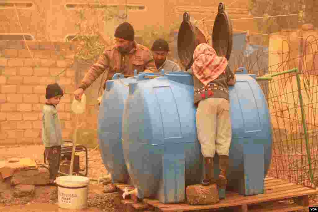 Keluarga-keluarga di Mosul mengumpulkan air dari sumur darurat yang dioperasikan dengan generator karena mereka tidak punya air yang mengalir atau listrik (2/12). (VOA/H.Murdock)