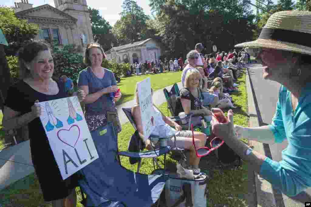 Muhammad Ali Memorial: Cathy Gutgsell, left, holds a sign as she is photographed while spectators wait for the arrival of Muhammad Ali's funeral procession to enter Cave Hill Cemetery, Friday, June 10, 2016, in Louisville, Kentucky.