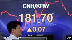 Seorang pegawai melewati papan nilai pertukaran mata uang di sebuah bank di Seoul, Korea Selatan.