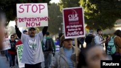 FILE - People hold signs as they gather outside a Federal Building while protesting against Immigration and Customs Enforcement (ICE) raids on Central American refugees in Los Angeles, California, Jan. 26, 2016.
