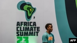 Mtu mmoja akisimama mbele ya nembo ya Mkutano wa Kitaifa wa Hali ya Hewa barani Afrika kabla ya mkutano barani Afrika 2023 katika Kituo cha Mikutano cha Kimataifa cha Kenyatta jijini Nairobi, Kenya Septemba 2, 2023.