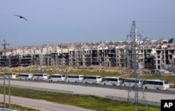 In this photo released by the Syrian official news agency SANA, buses carry Syrian citizens, who evacuated from the two pro-government villages of Foua and Kfarya, arrive at a handover point between the two sides on the outskirts of Aleppo, Syria, April 21, 2017.