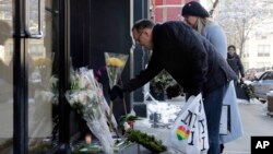 A couple adds to the flowers placed outside the apartment building of actor Phillip Seymour Hoffman, in New York, Feb. 4, 2014. 