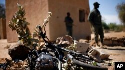 Malian soldiers stand by a motorcycle used by a suicide bomber at the entrance of Gao, northern Mali, Feb. 8, 2013.
