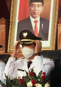 Gibran Rakabuming Raka, duduk di depan potret ayahnya Presiden Joko Widodo saat dilantik sebagai Walikota Solo di Jawa Tengah pada 26 Februari 2021. (Foto: AFP/Anwar Mustafa)