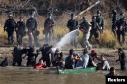 FILE - Police use pepper spray against protesters trying to cross a stream near an oil pipeline construction site near Standing Rock Indian Reservation, north of Cannon Ball, North Dakota, Nov. 2, 2016.