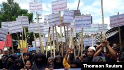 Rohingya refugees hold placards as they participate in a rally to observe World Refugee Day at the Rohingya refugee camp in Cox's Bazar, June 20, 2019.