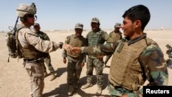 រូបឯកសារ៖ ទាហាន​អាមេរិក​ម្នាក់ (ឆ្វេង) បាន​ចាប់រលាក់ដៃ​ជាមួយ​ទាហាន​អាហ្វហ្គានីស្ថាន ក្នុង​អំឡុងពេល​ធ្វើសមយុទ្ធ​មួយ​នៅ​ខេត្ត Helmand ប្រទេស​អាហ្វហ្គានីស្ថាន កាលពី​ថ្ងៃទី៥ ខែកក្កដា ឆ្នាំ២០១៧។