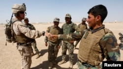 FILE - A U.S. Marine, left, shakes hands with an Afghan National Army soldier, during a training exercise in Helmand province, Afghanistan, July 5, 2017. 