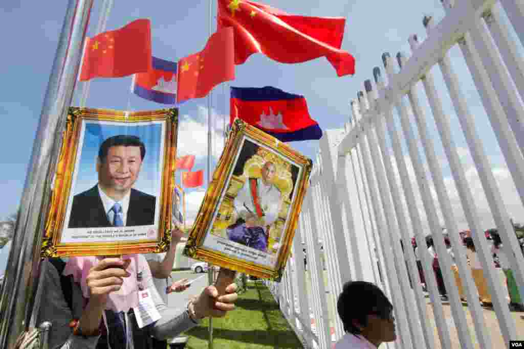 សិស្សនិស្សិត​ដាក់​បដា​រូប​ប្រធានាធិបតី​ចិន​លោក Xi Jinping និង​រូប​ព្រះមហាក្សត្រ​កម្ពុជា នរោត្តម សីហមុនី​ នៅ​ឯ​ព្រលានយន្តអន្តរជាតិ​ភ្នំពេញ​ ក្រុង​ភ្នំពេញ នា​ថ្ងៃ​ទី​១៣ ខែ​តុលា​ ឆ្នាំ២០១៦។ (ឡេង ឡែន/VOA)