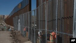 Workers continue work raising a taller fence in the Mexico-US border separating the towns of Anapra, Mexico and Sunland Park, New Mexico, Jan. 25, 2017.