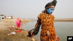 A young Indian boy dressed as Hindu God Shiva walks the banks of the River Ganges looking for alms from devotees on the first day of the nine-day Navratri festival, in Allahabad, India,Tuesday, Oct. 13, 2015. 