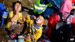 Anak-anak migran Suriah memakan susuk bubuk pada tempat penampungan sementara di kota Roszke, Hungaria selatan, Minggu (13/9).