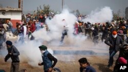 Protesting farmers run away from tear gas shells used by the police near Shambhu border that divides northern Punjab and Haryana states, some 200 kilometers (120 miles) from New Delhi, India, Feb.21, 2024. 