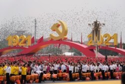FILE - Attendees wave Chinese flags during a ceremony at Tiananmen Square to mark the 100th anniversary of the founding of the ruling Chinese Communist Party in Beijing.