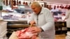FILE - Vendor Misi Kovacs prepares meat to sell at a market in Budapest, Hungary, Nov. 20, 2021. Around the world, rising consumer prices fueled by high energy costs and supply chain disruptions are putting a pinch on households and businesses.