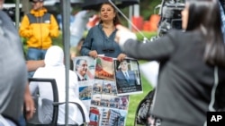 A woman holds images, some showing former Lebanon Prime Minister Rafik Hariri, outside the United Nations-backed Lebanon Tribunal in Leidschendam, Netherlands, Aug. 18, 2020.