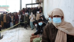 Afghans wait to receive food rations organized by the World Food Program (WFP) in Pul-e-Alam, the capital of Logar province, eastern of Afghanistan, Tuesday, Jan. 18, 2022.