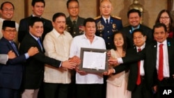 FILE - President Rodrigo Duterte, center, and leaders of the Moro Islamic Liberation Front, including Al Haj Murad Ebrahim, left, Mohagher Iqbal, right, and Ghadzali Jaafar, second from right, hold together the signed "Organic Law for the Bangsamoro Autonomous Region.