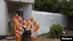 Des fossoyeurs sortant du Port Loko District Hospital en Sierra Leone (Reuters)