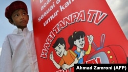 Seorang anak laki-laki memegang poster kampanye "Sehari Tanpa TV" di Jakarta, 20 Juli 2007. KPAI menggelar pertemuan dengan Komisi Penyiaran Indonesia guna membahas tayangan TV ramah anak, Rabu, 2 Juni 2021. (Foto: AFP/Arsip) 