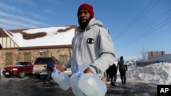 FILE - Lemott Thomas carries free water being distributed at the Lincoln Park United Methodist Church in Flint, Mich., Feb. 3, 2015.