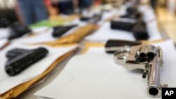 FILE - Chicago police display some of the thousands of illegal firearms confiscated in 2014. New data show homicides have surged recently in Chicago, Dallas, Las Vegas and Los Angeles.