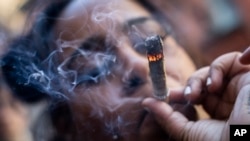FILE - A person smokes cannabis outside the Smacked 'pop up' cannabis dispensary location, Jan. 24, 2023, in New York.