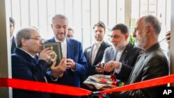 Menteri Luar Negeri Suriah Faisal Mekdad (kiri) mencium kitab Al-Quran dalam acara peresmian gedung konsulat Iran didampingi Menteri Luar Negeri Iran Hossein Amirabdollahia (kedua dari kiri) di Damaskus, Suriah, Senin, 8 April 2024. (Foto: Omar Samadiki/AP Photo)