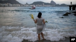 FILE - Many cultures have good luck charms or activities. In this photo, a woman offers flowers to Yemanja, goddess of the sea, for good luck in the coming year during New Year's Eve festivities on Copacabana beach in Rio de Janeiro, Brazil, Dec. 31, 2016. (AP Photo/Leo Correa)
