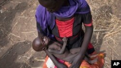 Adel Bol, 20, cradles as she her 10-month-old daughter Akir Mayen at a food distribution site in Malualkuel in the Northern Bahr el Ghazal region of South Sudan.
