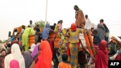 FILE - People, mostly women and children, internally displaced by Boko Haram militants, try to climb a truck protesting food shortages and a diversion of aid supplies meant for them, at a camp in Maiduguri, northeast Nigeria, on June 27, 2019.