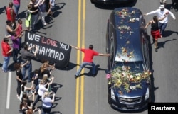 A well-wisher holding a banner touches hearse carrying remains of Muhammad Ali during funeral procession for the three-time heavyweight boxing champion in Louisville, Kentucky, June 10, 2016.