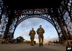 French soldiers patrol at the Eiffel Tower which remained closed on the first of three days of national mourning in Paris, Nov. 15, 2015.