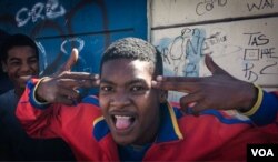 A young man postures, making a handgun gesture, in Cape Town's Hanover Park. Gang shootings are all too familiar in the township. (H. FitzPatrick/VOA)