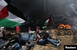 Palestinian demonstrators take cover from Israeli fire and tear gas during a protest against U.S. embassy move to Jerusalem and ahead of the 70th anniversary of Nakba, at the Israel-Gaza border in the southern Gaza Strip, May 14, 2018.
