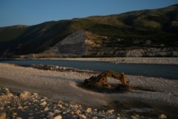 FILE - An abandoned bulldozer sits on the banks of the Vjosa River at the construction site of the Kalivac dam in Albania, June 23, 2019.
