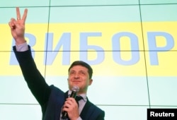 Ukrainian comic actor and presidential candidate Volodymyr Zelenskiy flashes a victory sign following the announcement of the first exit poll in a presidential election at his campaign headquarters in Kyiv, March 31, 2019.