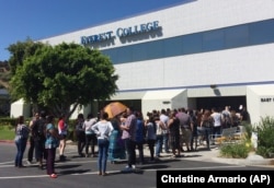 FILE - Students wait outside Everest College in Industry, California after it shut down all of its remaining 28 ground campuses in April 2015. The shutdown came after the U.S. Department of Education announced it was fining the for-profit institution.