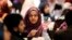 A young woman waves an American flag along with others at the beginning of a Muslim conference against terror and hate at the Curtis Culwell Center, Jan. 17, 2015, in Garland, Texas.