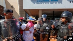 A masked anti-government protester is arrested by police as security forces disrupt an opposition march, coined "United for Freedom," in Managua, Nicaragua, Sunday, Oct. 14, 2018. 